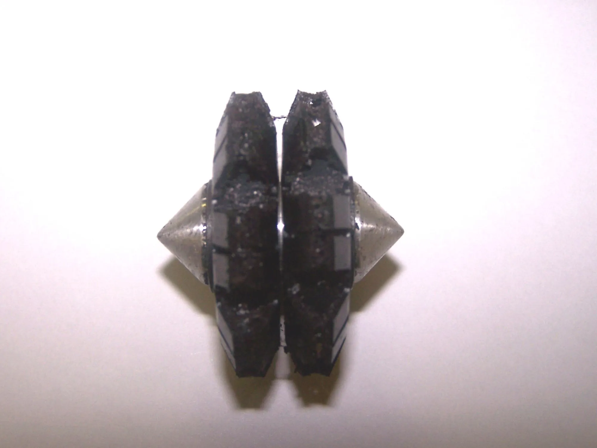 A Magnom core, two magnetic discs on a spindle, coated in black ferrous debris