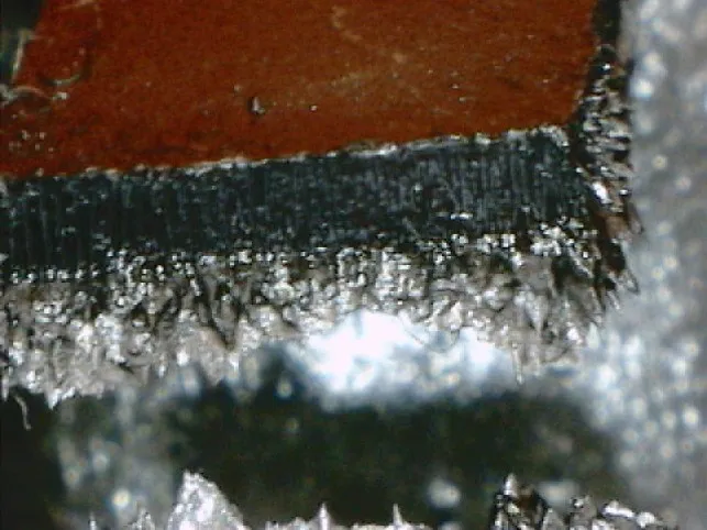 Ferrous particles standing on the edge of a magnetic core under a microscope