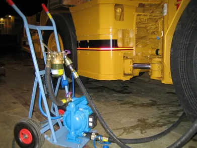 A filtration trolley with a Magnom unit connected by hoses to a large yellow machine